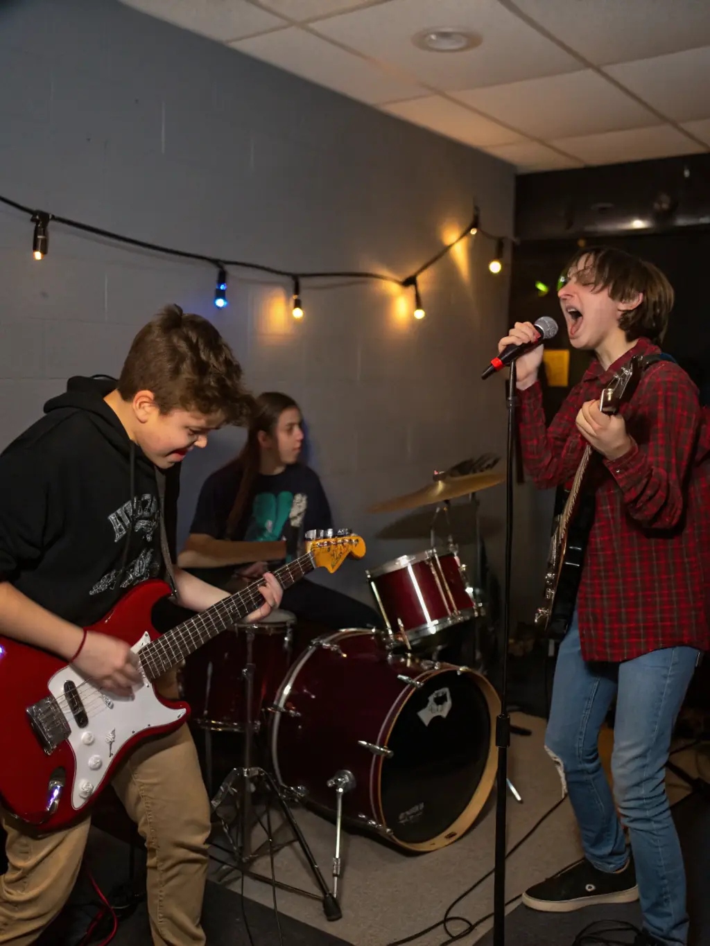 A dynamic image of teenagers collaborating in a band workshop, playing electric guitars, drums, and keyboards, with a focus on teamwork and creative expression.